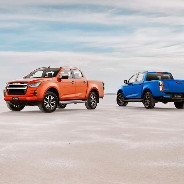Zwei ISUZU D-MAX pickups, einer in Orange und einer in Blau, nebeneinander geparkt in der Wüste. | © ISUZU