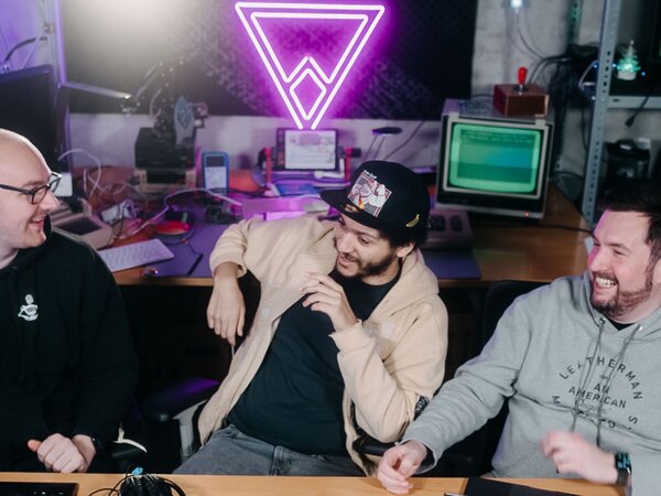 Three people laughing and having a good time in a tech-oriented workspace with neon lights. | © Photo: Ilja Kagan, 2022